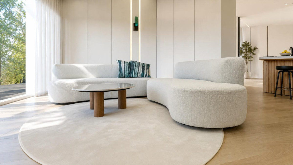 Divano Cloud Dancer Bouclé bianco con forme curve inserito in un soggiorno moderno e luminoso con arredamento minimal