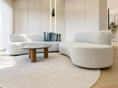 Divano Cloud Dancer Bouclé bianco con forme curve inserito in un soggiorno moderno e luminoso con arredamento minimal