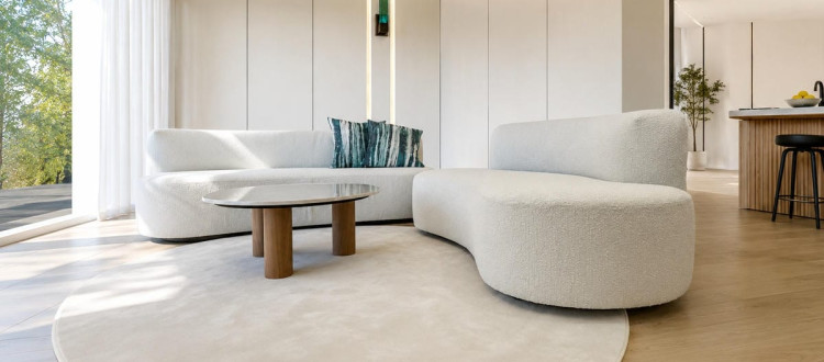 Divano Cloud Dancer Bouclé bianco con forme curve inserito in un soggiorno moderno e luminoso con arredamento minimal